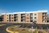 Modern apartment building with a sleek exterior featuring large balconies and ample parking in a serene neighborhood.