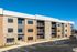 Modern three-story apartment building with stylish stone and brick exterior, featuring private balconies and ample parking in a serene setting.