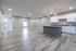 Modern open-concept kitchen and living area with sleek wood floors, ample cabinetry, and elegant pendant lighting.