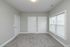 Bright and inviting room featuring plush carpet, sleek white doors, and a large window for ample natural light.