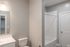 Modern bathroom with sleek white fixtures, a spacious shower area, and elegant lighting.