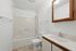 Bright and modern bathroom featuring a sleek bathtub, stylish vanity with mirror, and elegant tile flooring.