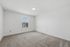 Bright and spacious unfurnished room with soft carpet flooring and a large window, perfect for customization.