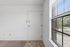Inviting entryway with natural light pouring through a large window adjacent to a neatly tiled area and plush carpet flooring.