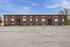 Charming brick apartment building with large windows and ample parking under a clear blue sky.