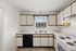 Bright and modern kitchen with sleek cabinetry, dual sink, and large window offering natural light.