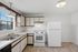 Bright and inviting kitchen with modern white appliances, ample cabinetry, and natural light from a large window.