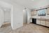 Bright, open kitchen with classic cabinetry and large window, seamlessly connecting to a welcoming hallway.
