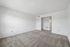 Bright and spacious living room with fresh carpet and modern white walls, leading into an elegant open doorway.
