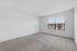 Bright and spacious room with large window, carpet flooring, and clean white walls, perfect for personalization and natural light.