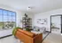 Inviting living room with a modern leather sofa, stylish shelving, and large window overlooking a scenic view.