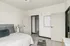 Bright and inviting bedroom with modern decor, featuring soft neutral tones and stylish wooden flooring.