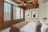 Chic urban bedroom with exposed brick walls, large windows, and modern artwork, providing a loft-style ambiance.