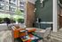Chic apartment lobby featuring modern seating, vibrant area rug, and floor-to-ceiling windows with urban views.