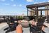 Chic rooftop lounge with cozy fire pit, modern seating, and stunning city views under a bright blue sky.