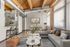Chic industrial-style apartment with exposed beams and ducts, featuring a cozy living area and modern dining nook. Bright, open space perfect for urban living.