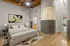 Chic bedroom with modern art, elegant bed, and stylish glass block wall, highlighting architectural charm and warm wood accents.