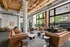 Modern loft-style living area with high ceilings, exposed ductwork, and large windows. Features stylish leather sofas, cozy armchairs, and contemporary decor providing a welcoming ambiance.