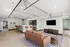 Contemporary open-concept apartment with stylish bar stools, cozy brown sofa, and a sleek wall-mounted TV.