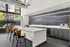 Contemporary apartment kitchen with sleek countertops, elegant bar seating, and abundant natural light through large windows.