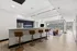 Modern open-concept apartment with sleek kitchen bar, stylish seating, and expansive city views from large windows.