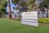 Entrance sign of The Hazelwood Apartments lush with greenery and clear blue sky