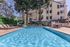 Refreshing apartment pool area with sun loungers and umbrellas surrounded by greenery.