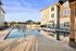 Modern apartment complex with a luxurious outdoor swimming pool, surrounded by stylish lounge chairs and umbrellas, perfect for relaxation.