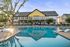 Charming apartment complex with a serene pool, comfortable lounge chairs, and lush greenery, perfect for relaxation and leisure.
