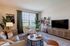 Inviting living room with modern decor featuring a cozy leather sofa, elegant armchair, stylish coffee table, and large TV for relaxation.