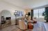 Chic living room with contemporary decor, featuring a cozy sectional sofa, stylish accent chairs, and bright natural light through large windows.