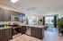 Contemporary kitchen and living area with stainless steel appliances, elegant dark wood cabinets, stylish lighting, and large windows for abundant natural light.