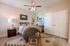 Elegant bedroom with cozy decor, featuring a soft bed with warm blankets, decorative pillows, and modern art pieces, complemented by natural light and a stylish ceiling fan.