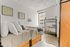 Bright and inviting bedroom with stylish modern decor, featuring a cozy bed, elegant desk, and large window showcasing a city view.