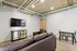 Modern living space with sleek leather seating, stylish exposed ductwork ceiling, and a mounted flat-screen TV for ultimate comfort and entertainment.