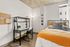 Cozy bedroom featuring a stylish desk with a modern chair, adding a functional workspace beside a comfortable plush-bed adorned with vibrant cushions and a warm orange throw.