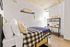 Cozy bedroom with a stylish plaid bedspread, modern desk, and chic decor, perfect for restful nights and productive days.