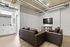 Modern living area with sleek leather sofas, large wall-mounted TV, and contemporary exposed ductwork.
