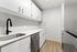 Modern kitchen with sleek white cabinets, a stylish black faucet, and stainless steel appliances, offering a blend of functionality and elegance.