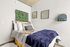 Chic bedroom with modern decor, featuring a cozy bed with a stylish headboard, lush green wall art, and minimalist shelving for a serene ambiance.