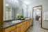 Bright and modern bathroom with double sinks, sleek countertop, and doorway leading to a cozy bedroom with stylish decor.