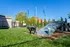 Vibrant pet-friendly outdoor area featuring a black dog with a red collar enjoying an agility ramp under a clear blue sky.