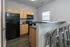 Modern kitchen with sleek black appliances, natural wood cabinetry, and a stylish breakfast bar with industrial stools.