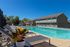 Inviting apartment complex pool area with sun loungers, vibrant potted plants, and clear blue skies, perfect for relaxation and socializing.