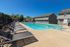Inviting outdoor pool area with modern sun loungers and clear blue water, perfect for relaxation and enjoyment under a bright blue sky.