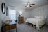 Cozy and elegantly furnished bedroom with a plush bed, stylish desk, and natural light, perfect for relaxation and work.