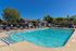Inviting outdoor pool area with modern sun loungers, surrounded by vibrant greenery on a sunny day.