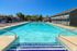 Inviting outdoor swimming pool surrounded by comfortable lounge chairs under a vibrant blue sky, perfect for relaxation and leisure.