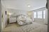 Elegant bedroom with neutral tones, featuring a plush bed, modern furnishings, and ample natural light from large windows.