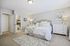 Bright and inviting bedroom with elegant decor, featuring a plush bed, stylish dresser, and cozy ambiance.